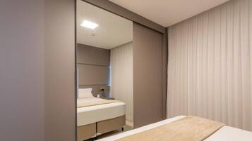 Een slaapkamer met een bed, nachtkastje en spiegel.