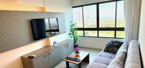Una sala de estar moderna con un televisor de pantalla plana montado en la pared, un sofá, una mesa de centro y una planta en maceta.