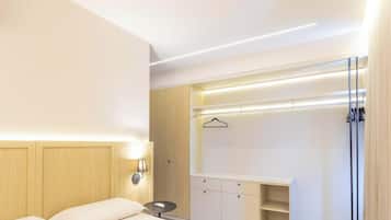 Ein Hotelzimmer mit Bett, Nachttisch, Lampe, Kleiderschrank und einer Garderobe.