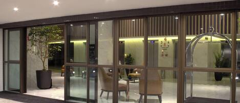 A hotel lobby with a reception desk, seating area, and a large potted plant.