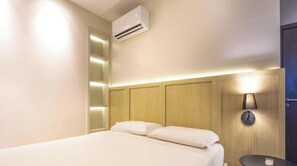A hotel room with a bed, an air conditioning unit, a bedside table, and a wall-mounted lamp. - Complexo Heron Marinho Flats (Campina Grande)
