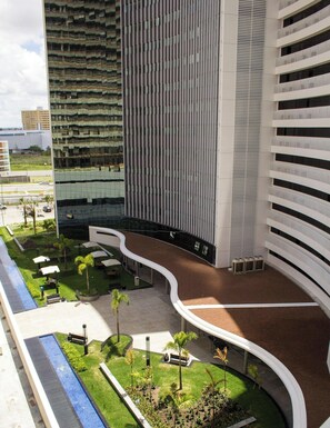 Un edificio moderno con un camino curvo, asientos al aire libre y vegetación.