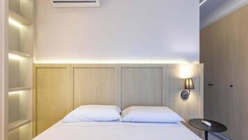 Habitación de hotel con cama, mesita de noche, lámpara de pared y armario empotrado.