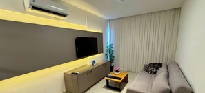 A modern living room with a flat-screen TV, a sofa, a coffee table, and a potted plant. - Complexo Heron Marinho Flats (Campina Grande)