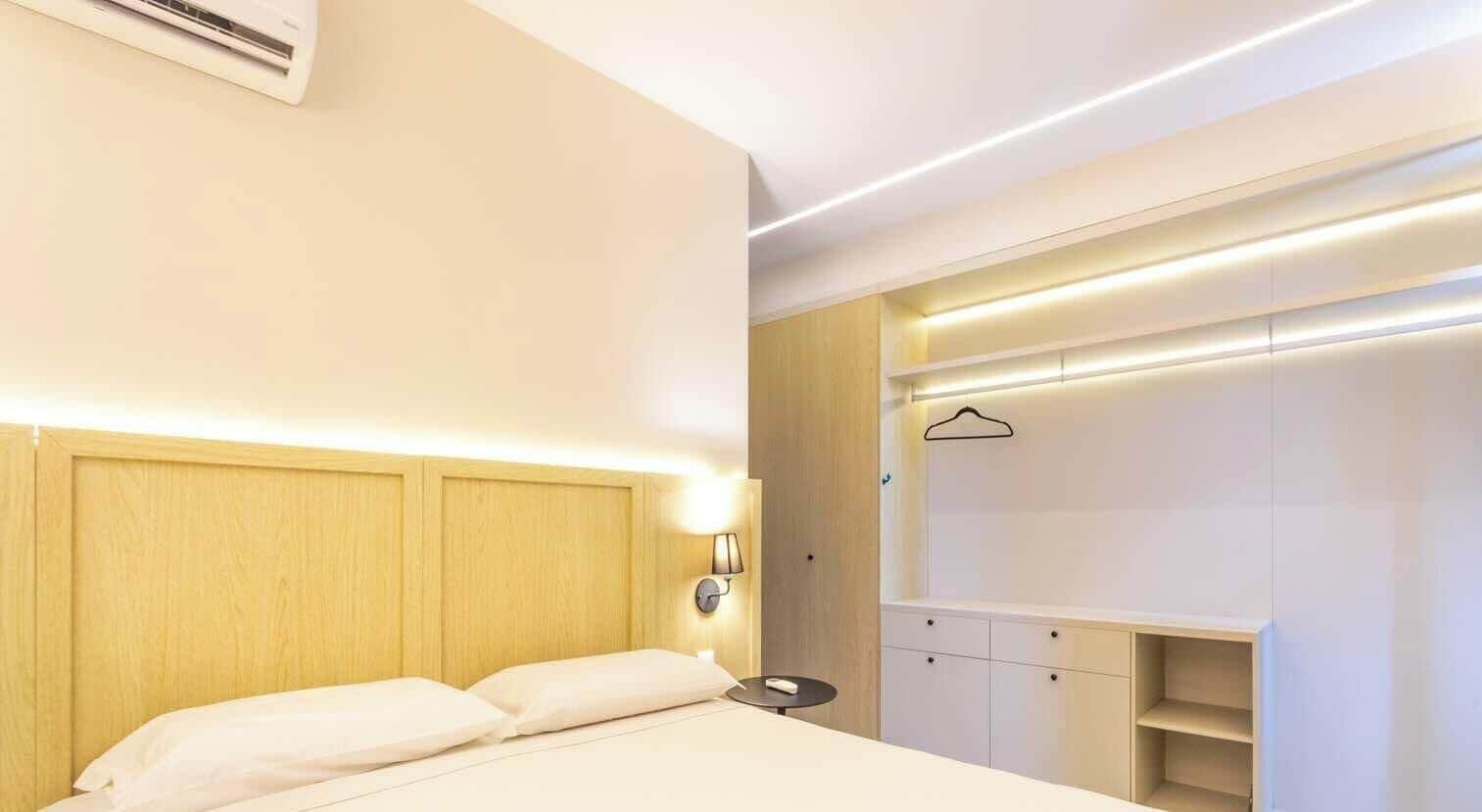 A modern hotel room with a bed, bedside table, and a built-in wardrobe.