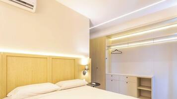 A modern hotel room with a bed, bedside table, and a built-in wardrobe.