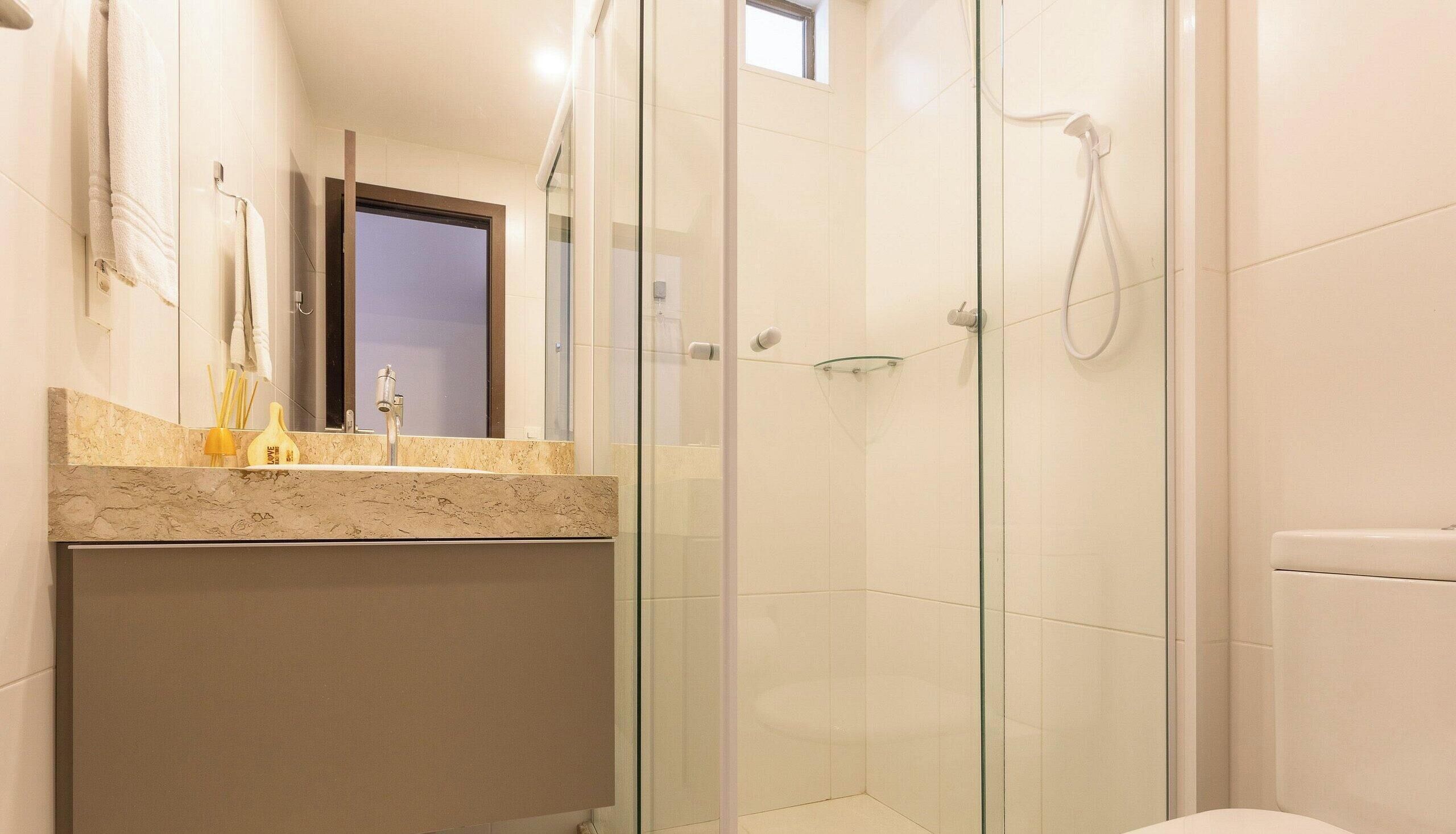 Ein modernes Badezimmer mit Duschkabine aus Glas, Marmorplatte und sichtbarer Toilette.