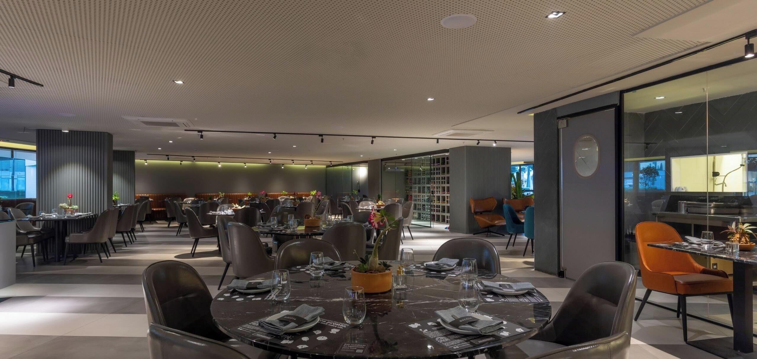 Un restaurant moderne doté de plusieurs tables, de chaises et d’un plafond orné d’un motif original.