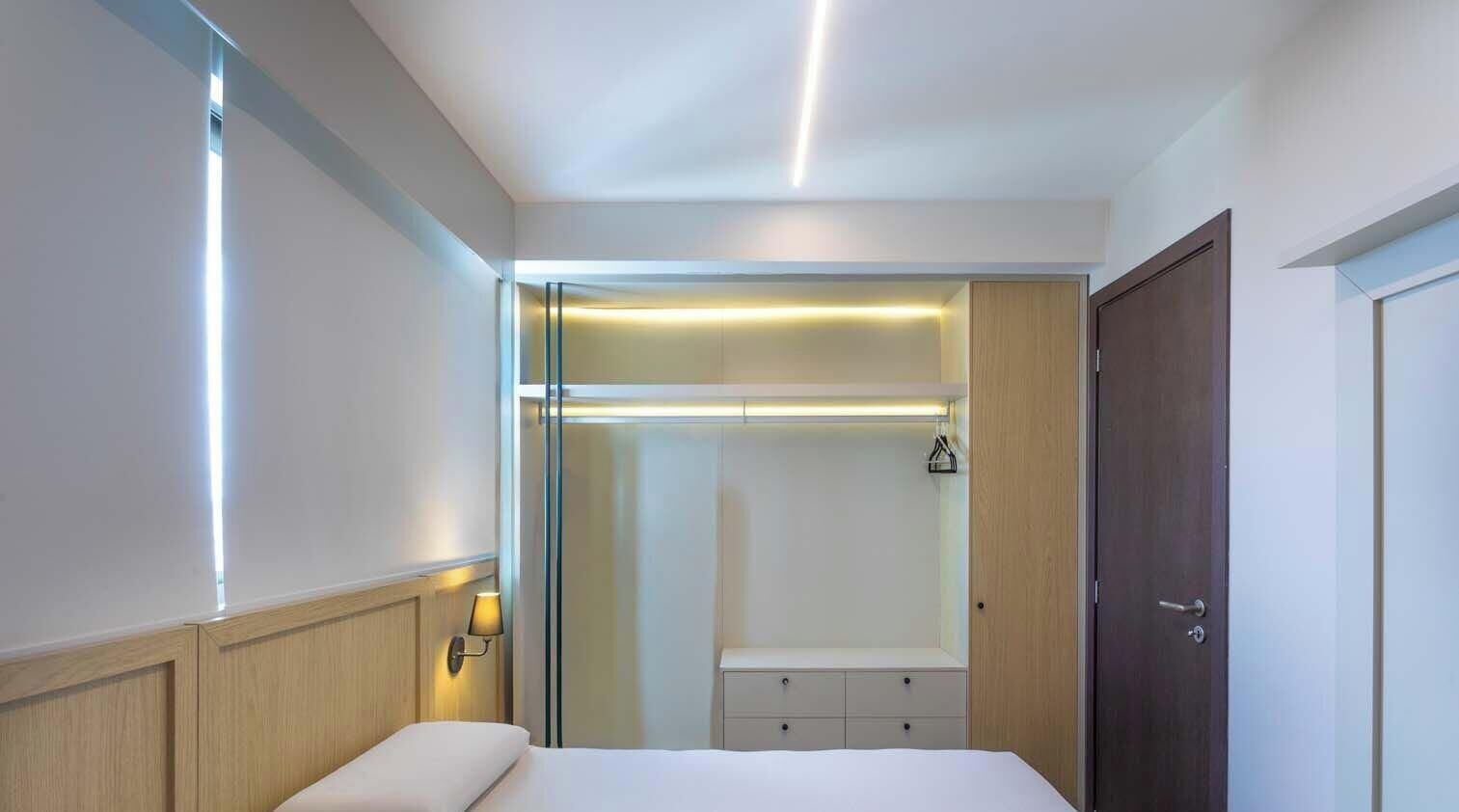 Une chambre d’hôtel comprenant un lit, une armoire et un dressing avec un miroir.