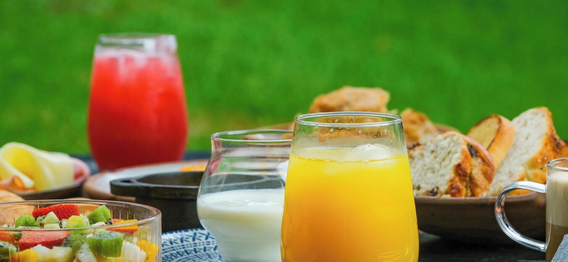 A breakfast setting with a glass of orange juice, a glass of milk, and a fruit salad.
