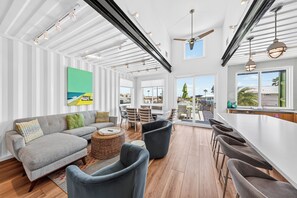 A spacious living area with a sofa, chairs, a dining table, and a view of the outdoors.