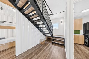 Step into your modern retreat with sleek hardwood floors and industrial-chic staircase leading to your bedrooms above.