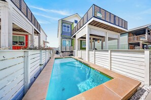 A residential property with a swimming pool, a covered outdoor area, and a two-story building with a balcony.