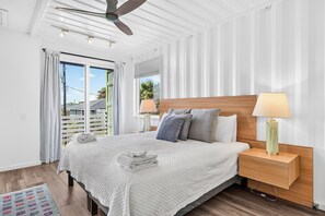 A hotel room with a bed, nightstands, a ceiling fan, and a view through the window.