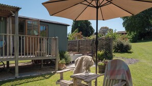 A wooden deck with a table and chairs, a covered seating area, and a fire pit. - Hurdlemakers Hut (Dorchester)