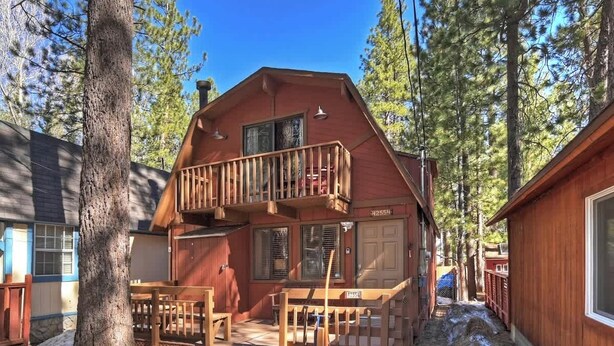 Eine Holzhütte mit einer Holzterrasse, einer überdachten Veranda und einer Garage.