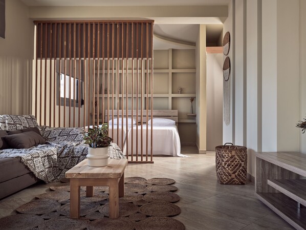 A modern living room with a sofa, a wooden table, and a bed with a headboard.