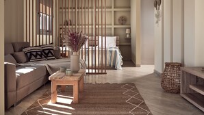 A modern living room with a sofa, a coffee table, and a bed with a striped bedspread. - Laura Suites (Zakynthos)