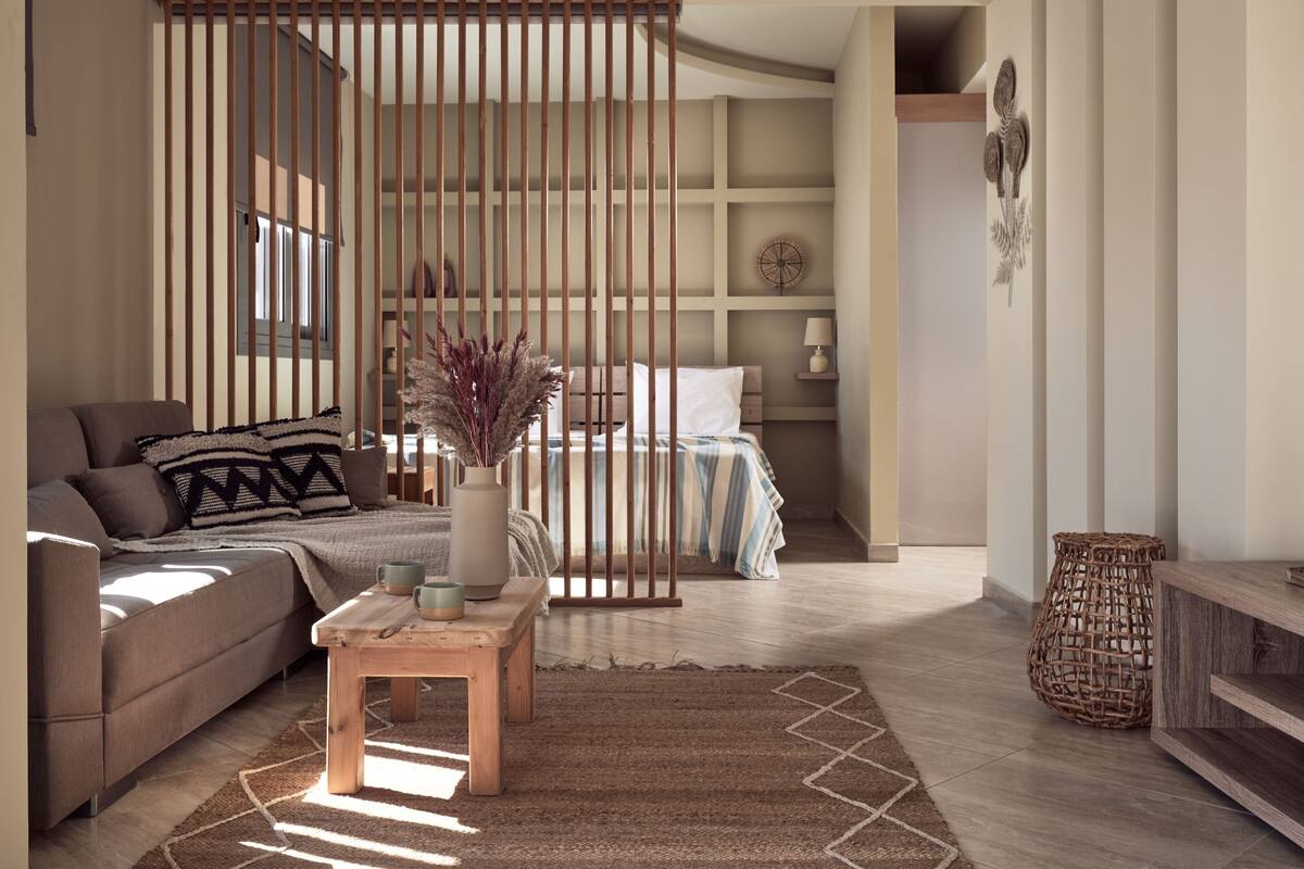 A modern living room with a sofa, a coffee table, and a bed with a striped bedspread.