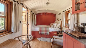 A cozy room with a bed, a wooden table, a chair, and a window. - Spindleberry Hut (Dorchester)