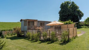 A single-story house with a fenced yard, a large tree, and a wooden fence. - Spindleberry Hut (Dorchester)