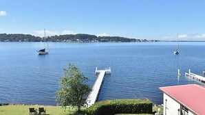 A calm lake with sailboats, a dock, and a distant shoreline with buildings. - Sparkling Waters - Jetty & Games Room! (Rathmines)