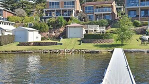 A residential area with a dock extending into a body of water, surrounded by houses and greenery. - Sparkling Waters - Jetty & Games Room! (Rathmines)