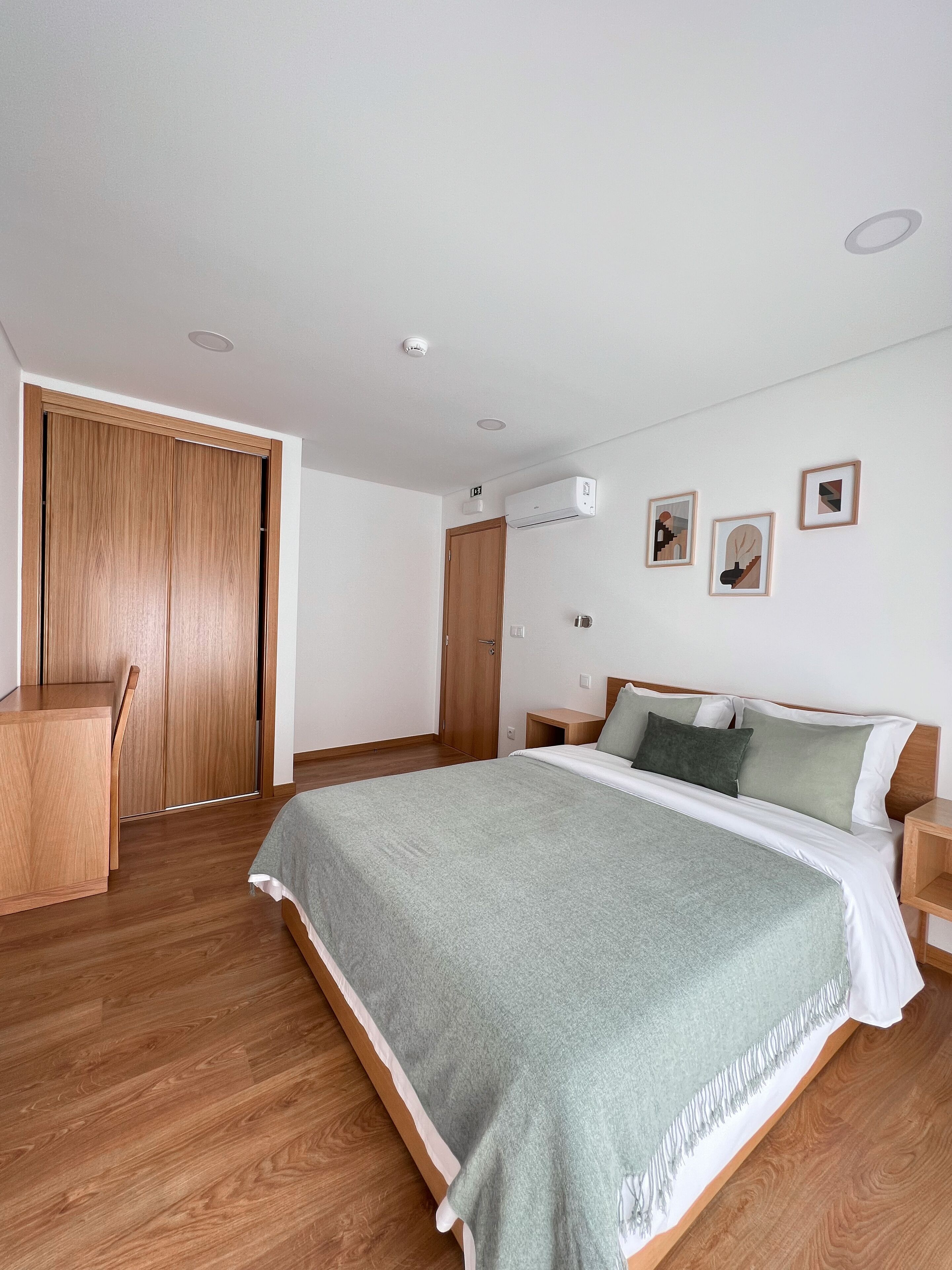 A bedroom with a bed, wooden wardrobe, and a desk.