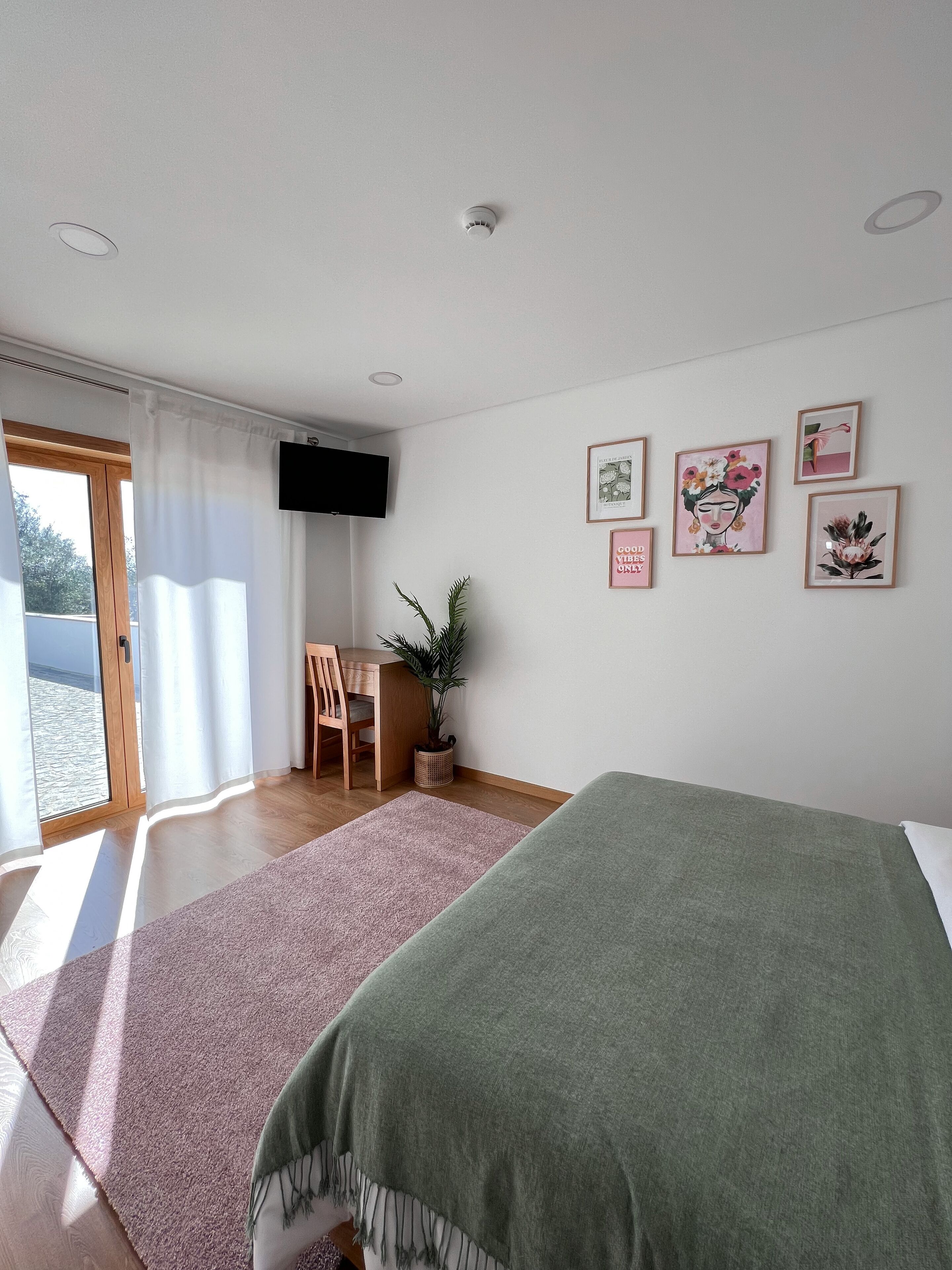 Un dormitorio con cama, escritorio, silla, televisor y ventana con cortinas.