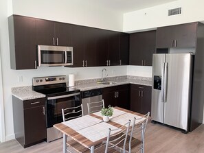 A modern kitchen with dark cabinets, stainless steel appliances, and a granite countertop. - Little Habana apartments (Miami)