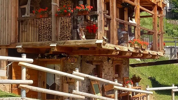 A wooden chalet with multiple balconies, stone walls, and a stone staircase leading to the entrance. - Chalet-Tabia'al Sol romantic apartment with breathtaking views in the Dolomites (Pecol)