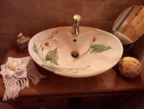 Ein Waschbecken mit floralem Dekor, eine Seifenschale und ein dekorativer Gegenstand auf der Ablagefläche.