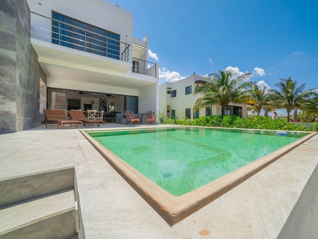A modern building with a pool, outdoor seating, and palm trees.