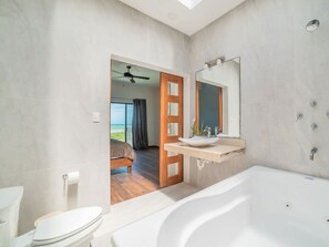 Un baño moderno con bañera, lavamanos y un espejo grande.