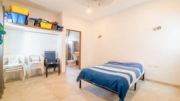 A bedroom with a bed, a desk, and a chair. There are storage boxes on the wall and a ceiling fan.