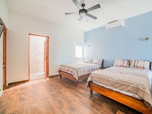 Un dormitorio con dos camas, ventilador de techo y aire acondicionado.