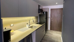 Una cocina compacta con un lavamanos, estufa y refrigerador.