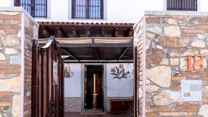 Una entrada de paredes de piedra con una verja de metal, un patio con baldosas y un cartel con el número 18.