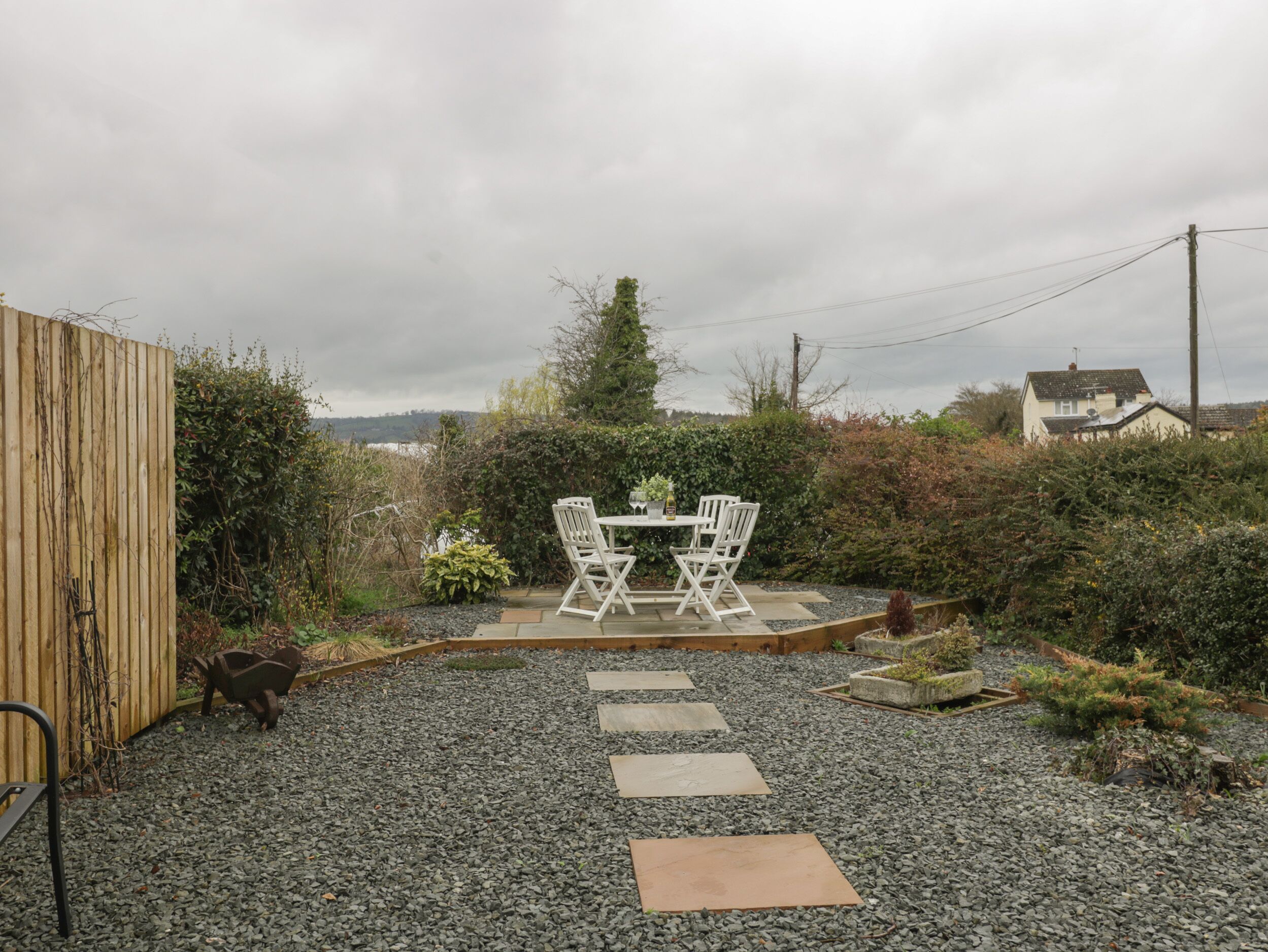 A patio with a table and chairs, surrounded by a gravel path and greenery.