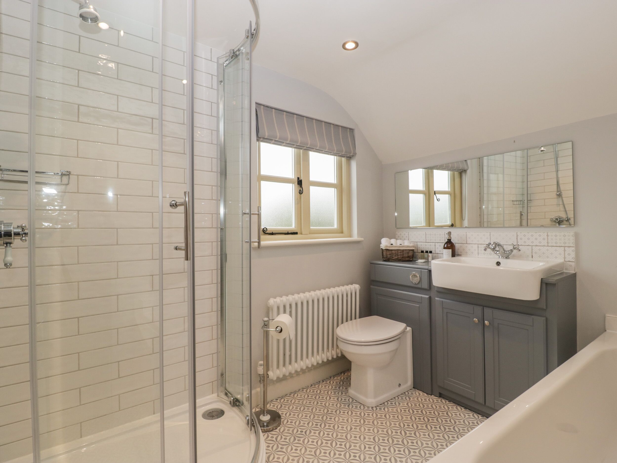 A bathroom with a glass-enclosed shower, a toilet, a sink, and a window with a view.