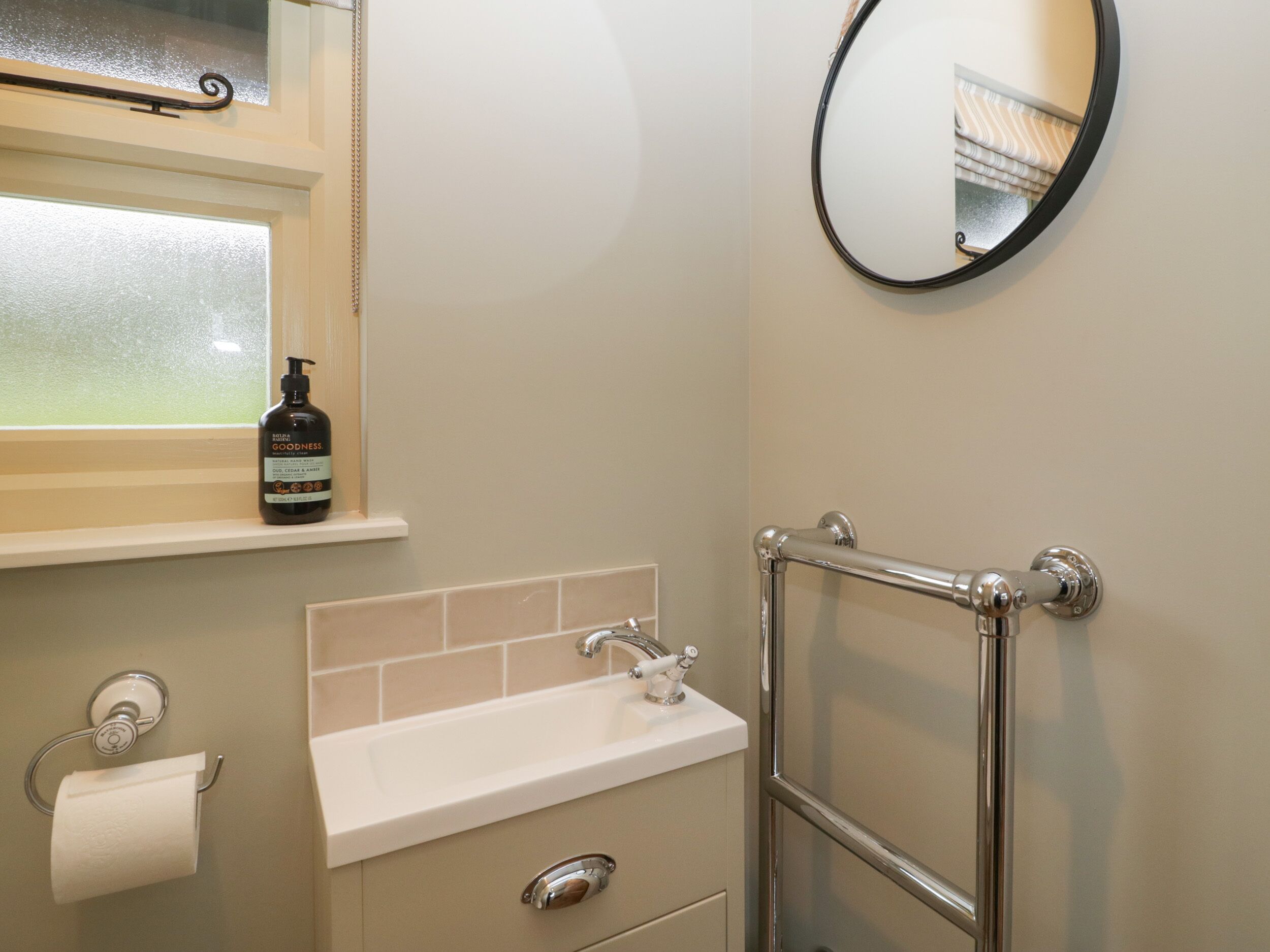 A bathroom with a sink, mirror, and toilet paper.