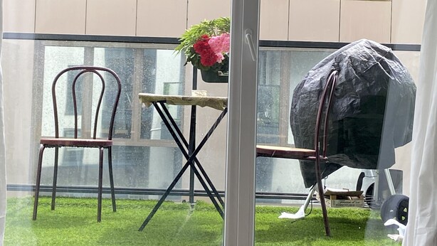 Un balcon avec un barbecue, une chaise et une petite table sur laquelle est posée une plante en pot.