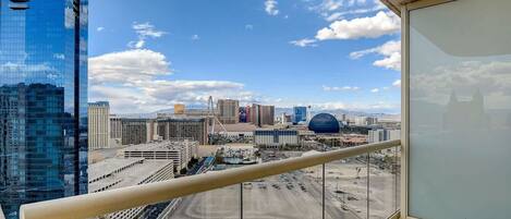 A cityscape with modern buildings, including a distinctive dome-shaped structure, viewed from a balcony with a clear sky.