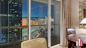 A hotel room with a large sliding glass door leading to a balcony with a city view.