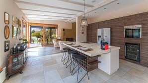 Una cocina moderna con una isla central, taburetes de bar y electrodomésticos integrados.