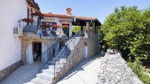 Ein Gebäude aus Stein mit einem Balkon, einer Treppe und einer Steinmauer.