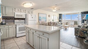 A spacious kitchen with white cabinetry, a large island, and a dining area with a view of the ocean. - 0112 Waters Edge Resort 3 Bedroom Condo by RedAwning (Murrells Inlet)