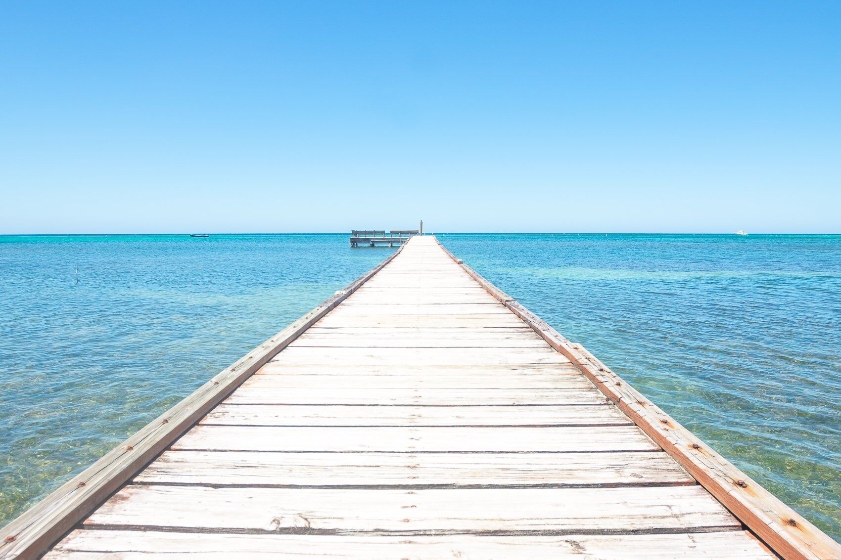 A wooden pier extending into a clear blue sea.