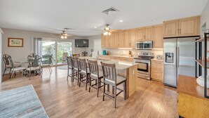 A modern kitchen with wooden cabinets, stainless steel appliances, and a central island with bar stools.