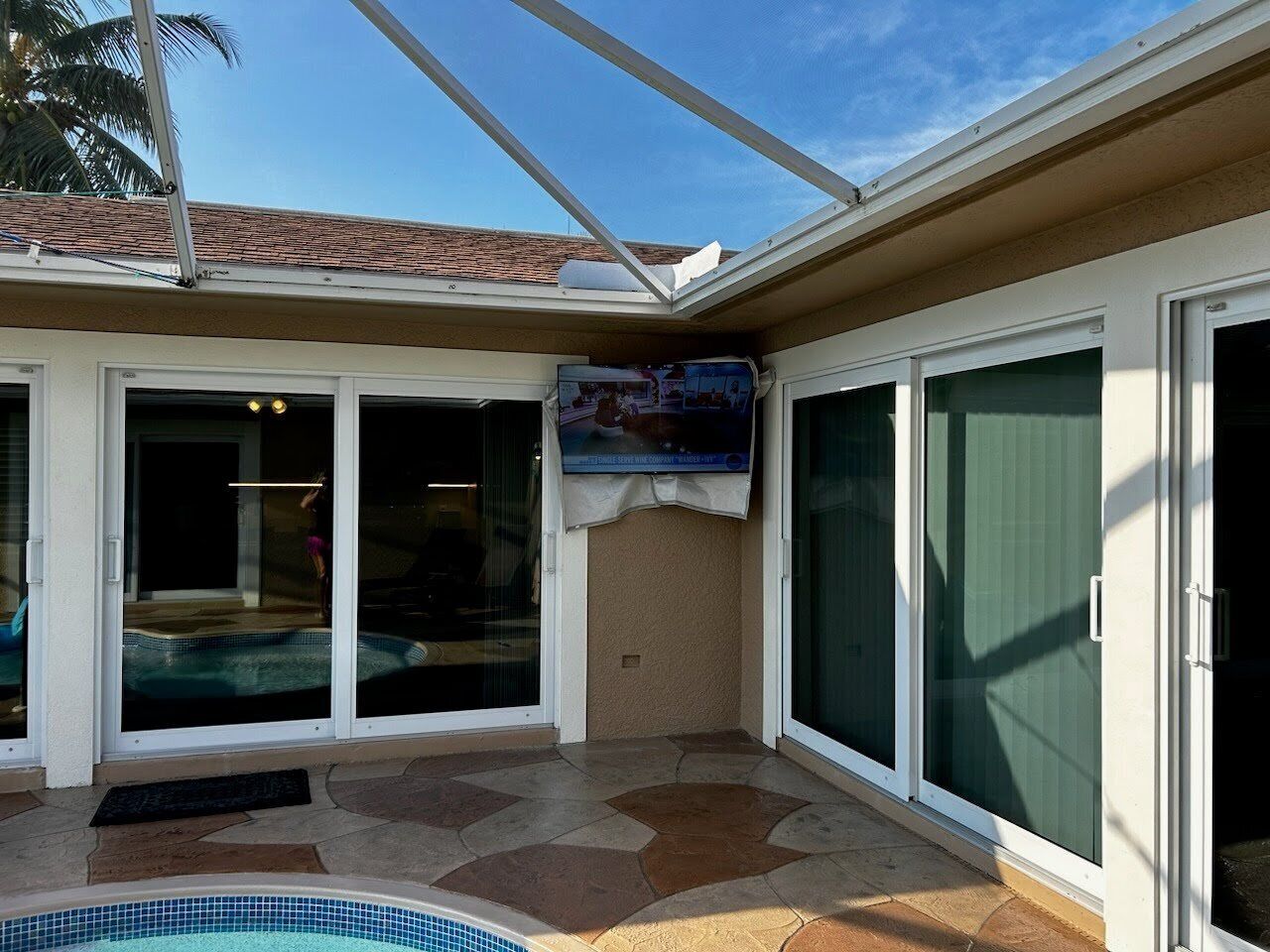 A covered patio area with a swimming pool, sliding glass doors, and a tiled floor.